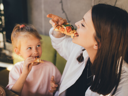 Child and mother eating pizza