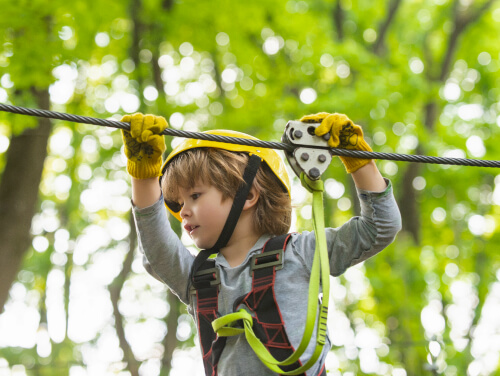 A happy child zip lining between trees
