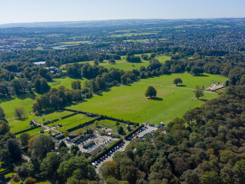 Aerial view of Graves Park in Sheffield with green fields, trees and a car park