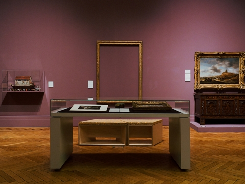 A table with a display in Manchester Art Gallery with a purple wall in the background