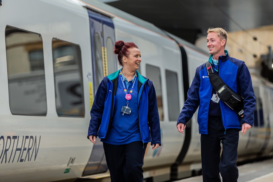 Two northern colleagues walking next to a train on a platform 