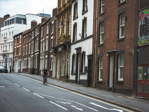A man riding a bicycle down a cloudy street in Sheffield