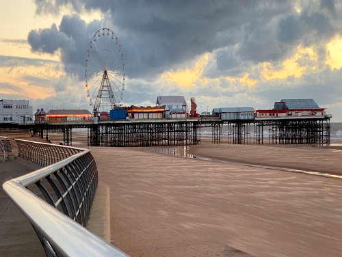 A pier with lots of arcade buildings on it as well as a Ferris wheel.